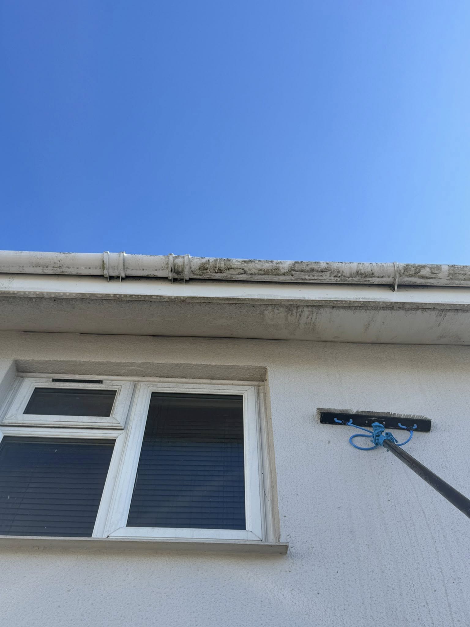 Pole and brush being used to clean gutters on a house in Weymouth